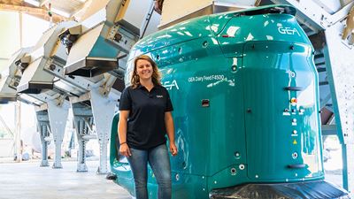 Dairy worker Clémence Poussier from France stands in front of a GEA automatic feeding robot.