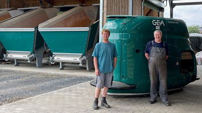 Dairy farmers Johannes Nickel and his father from Germany stand in front of a GEA automated feeding robot.